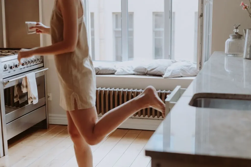 Woman in kitchen holding a coffee mug in morning light — 7 morning habits for an easier whole day