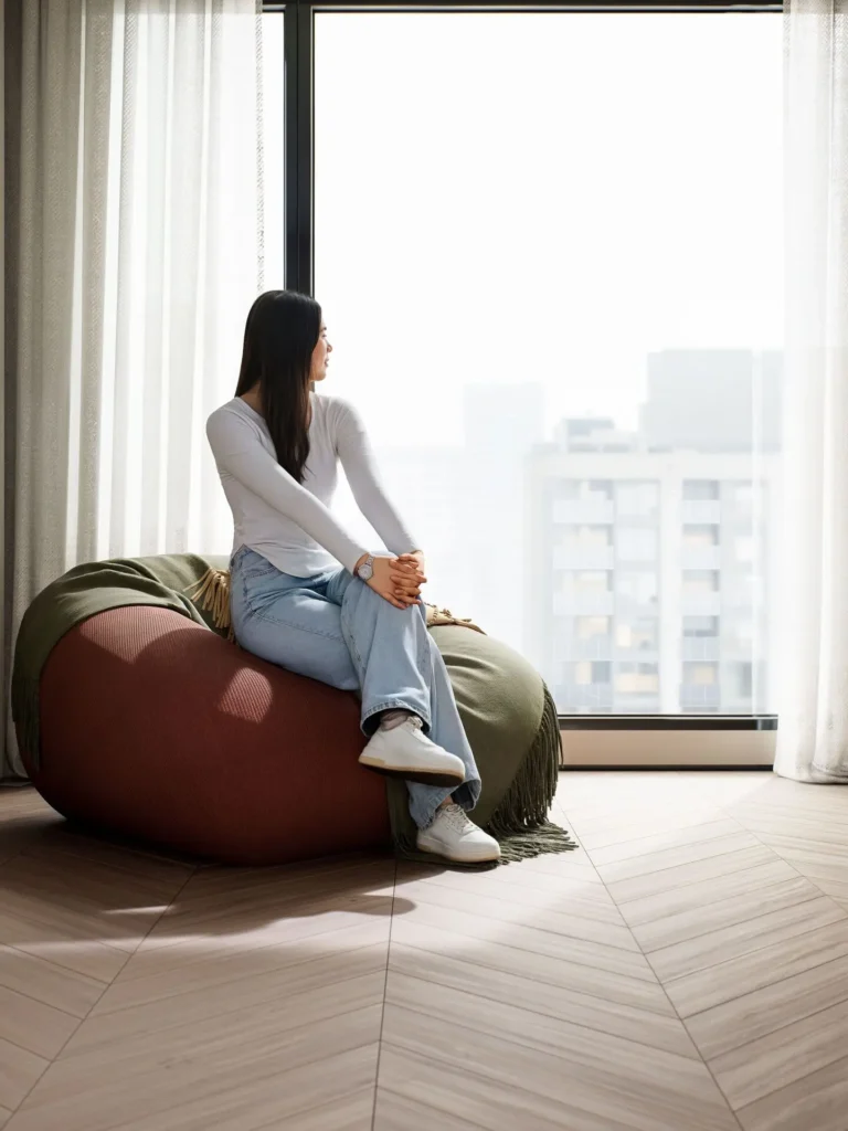 Woman sitting quietly by a window in a minimal space — the mindset shift that helps you feel more grounded