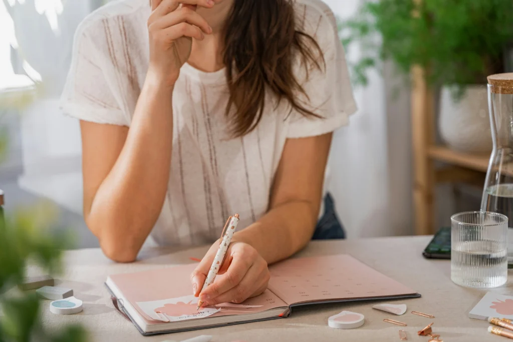 Woman writing in a planner — simple daily habits that make life feel more organized
