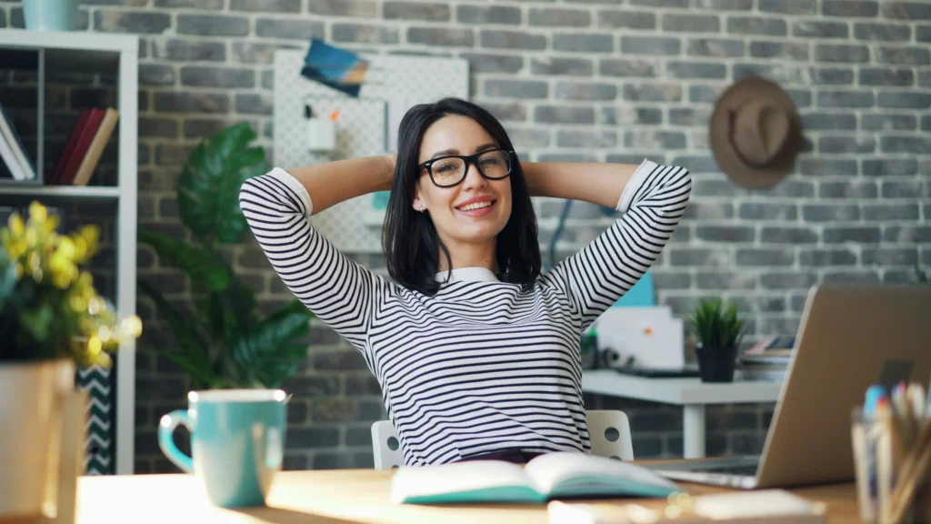 Woman relaxing at her desk with coffee and a notebook — habit stacking ideas for busy women